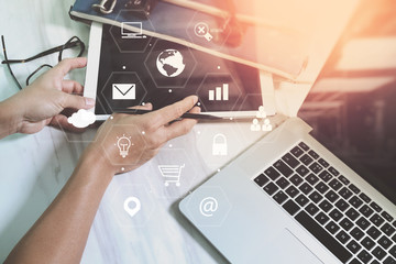 Poster - businessman working with laptop computer and digital tablet and suitcase on wooden desk in modern office with virtual icons interface