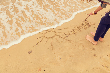 Girl drawing a sun in the sand of ocean / sea beach.