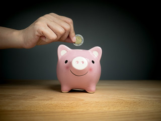 hand add coin to piggy bank save coin, time and money concept.