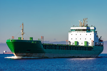 Green cargo ship moving in still water of Baltic sea