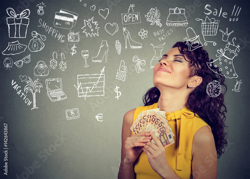 Fotografía Young woman with money dreaming how to spend it all
