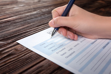 Wall Mural - Woman filling resume form on wooden table, closeup