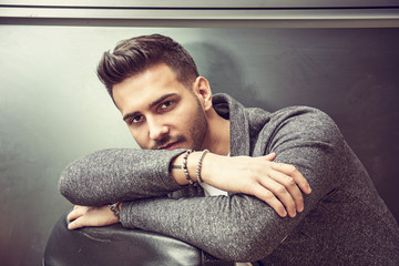 Wall Mural - Handsome young man wearing grey sweater, on dark background