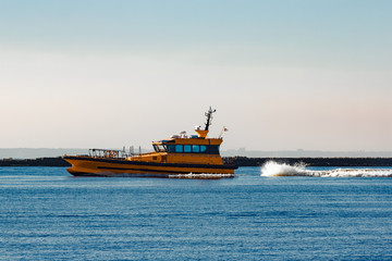 Sticker - Orange pilot ship moving at speed past the breakwater dam