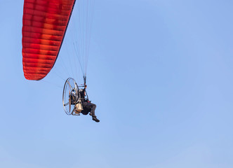 rear view paraglider flying with paramotor on  blue sky  background