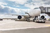 The white Unrecognizable plane at the airport takes passengers through a telescopic ladder