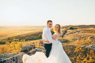 Wall Mural - stylish gorgeous couple newlyweds standing on the rocks in the mountains