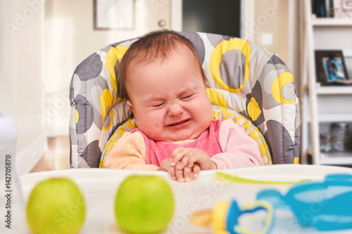 crying baby eating food on kitchen Buy this stock photo