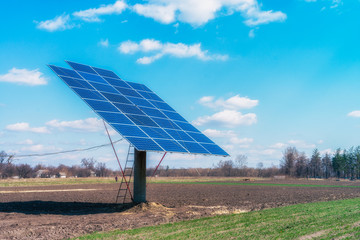 Solar panels on the green field in sunny weather. Vivid colorful image.