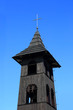 Drewniana dzwonnica kościelna, zbliżenie na tle błękitnego nieba.