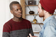 © wayhome.studio - Interracial friendship, people, youth and happiness. Stylish bearded hipster in hat explaining something while having conversation or dispute with his African American friend dressed in sweater