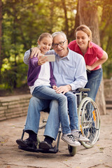 Wall Mural - selfie time- granddaughter, daughter and disabled man in wheelchair .