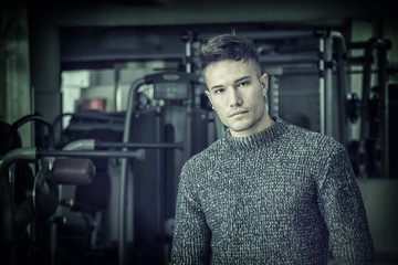 Wall Mural - Handsome white asian young man wearing grey sweater, standing indoor in dark place