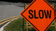 Slow down red banner traffic sign on the road with car in background. Road slow down for safe concept.