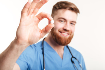 Portrait of a young male medical doctor offering a pill