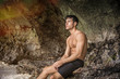 © theartofphoto - Half body shot of a handsome young man standing on a beach in Phuket Island, Thailand, shirtless wearing boxer shorts, showing muscular fit body, looking away to a side