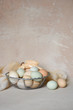 © Kelly - Easter still life of organic pastel colored eggs in a wire basket with a generic antique ceramic rabbit on a rustic canvas background