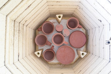 Overhead View Of The Bottom Shelf Of A Kiln Being Loaded With Pottery For A Glaze Firing