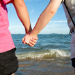 © xy - Summer couple holding hands in front of the sea.