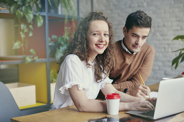 Two young professionals or students woman man happy with business meeting, smiling and talking about project. Office blue wall background