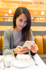 Wall Mural - Young Woman use of mobile phone in restaurant