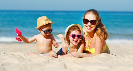 Happy family mother and children play and laugh on beach