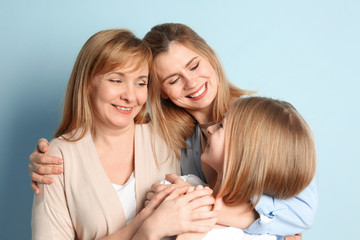 Wall Mural - Happy young woman with her mother and daughter on color background