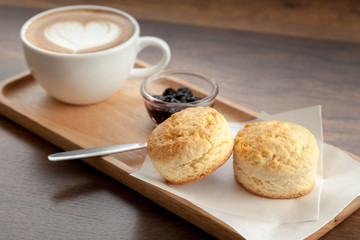 Wall Mural - Coffee cup of latte art served with scones and homemade blueberry jam on wooden background (Selective focus)