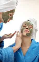 Wall Mural - Close-up Portrait of two beautiful looking womans with a facial clay mask.