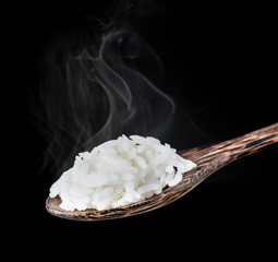 Wall Mural - Cooked rice in a wooden spoon with smoke over dark background