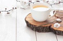 White Cup Of Hot Tea With Spring Flowers On A Light Wooden Background