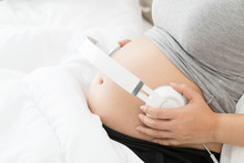 Belly Of Pregnant Women And Headphones For Listening Music