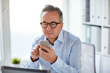 Canvas Print - businessman with laptop texting on smartphone