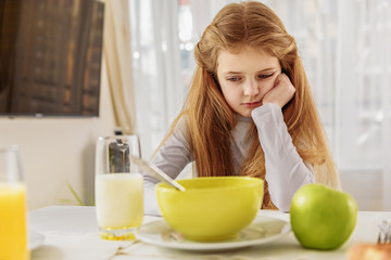 Sad female kid refuses healthy food