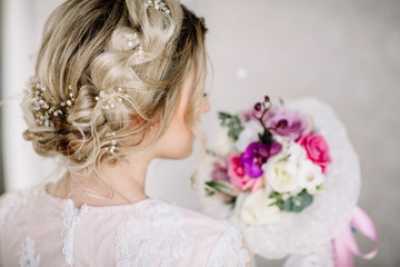 Beautiful girl in tender lacy dress with bouquet flowers peonies in hands standing against floral background in flower shop. Joyful asian female florist. Shy fashion model looking down and smiling.