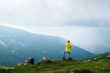 Fototapeta Do pokoju - Girl in bright clothes in the mountains admires the view before storm