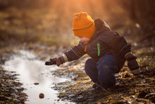 Little Boy Playing In Puddle At Springtime