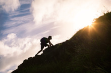 Young Man Climbing Up A Mountain. Self Improvement And Life Goals Concept.


