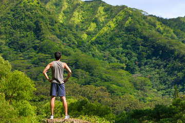 Fit active lifestyle. Young man standing against a green mountain view. (location Hawaii) 