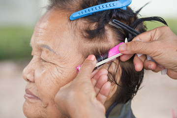 Wall Mural - hand of a hairstylist doing a perm rolling hair of senior woman