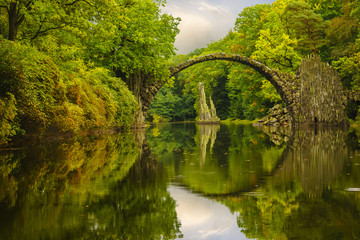  Autumn, cloudy evening over Devil's bridge in the park Kromlau, Germany