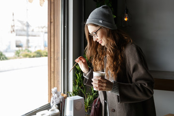 Sticker - Happy attractive young woman drinking coffee in cafe