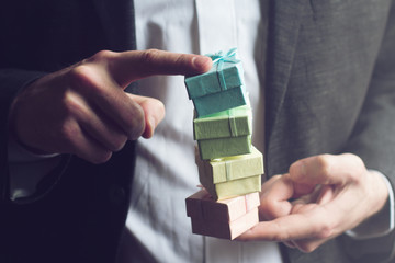 Wall Mural - Man holding small gift boxes with his index fingers