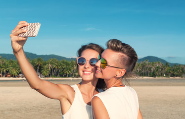 Two happy girlfriends making selfie on the coast of tropical sea