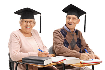 Poster - Cheerful seniors with graduation hats sitting in school chairs