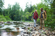 © pressmaster - Happy hikers walking along river in the forest