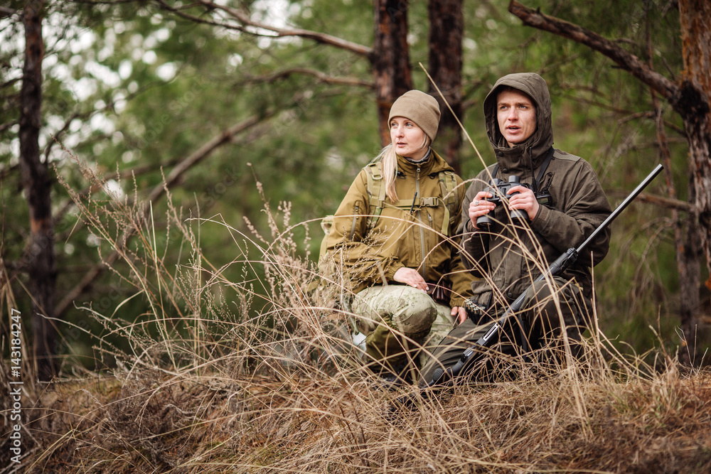 two hunters with binoculars ready to hunt, holding gun and walking in ...