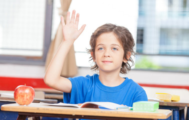 Confident boy at school raising hand