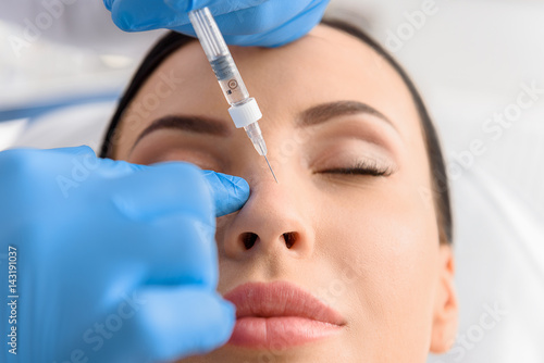 Fotografia  Serene female receiving collagen in nose