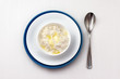 Rice porridge with milk and butter in a white bowl on a white background for breakfast.